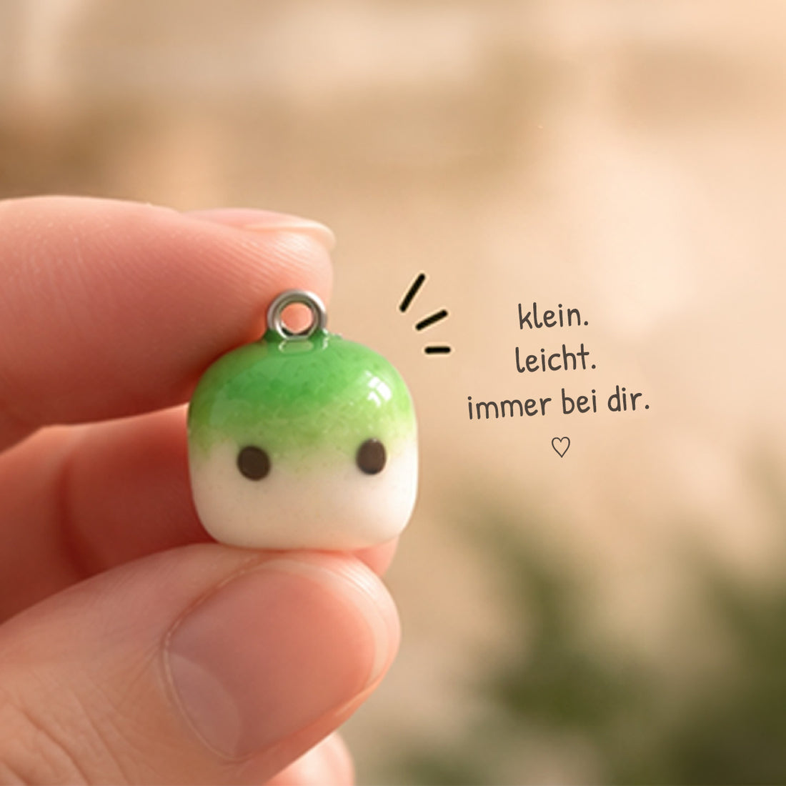Nahaufnahme eines kleinen Matcha Clay Charms mit Metallöse