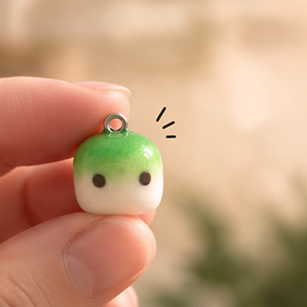 Winziger grüner Matcha Mallow Charm zwischen zwei Fingern